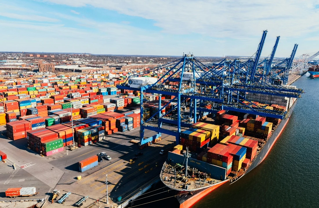 A cargo shipping and container port scene illustrating logistics planning, supply chain timing, and delivery coordination for pride merch and event apparel