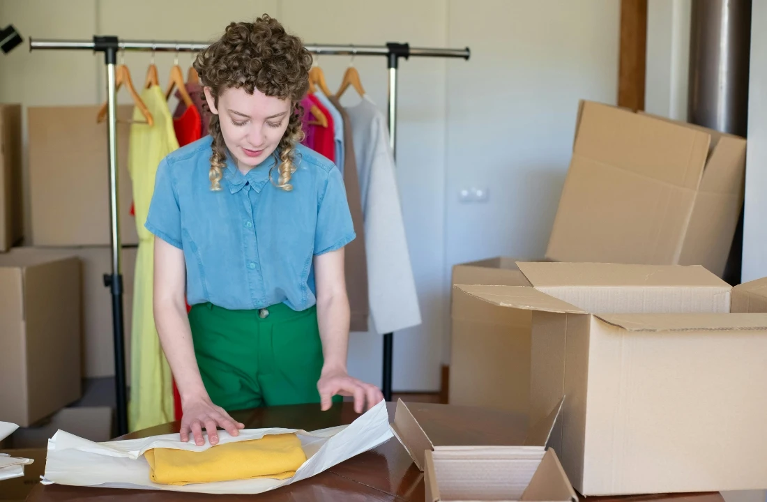 A small business owner packing apparel in eco-friendly boxes, suitable for discussing pride apparel packaging, branded presentation, and premium unboxing experience