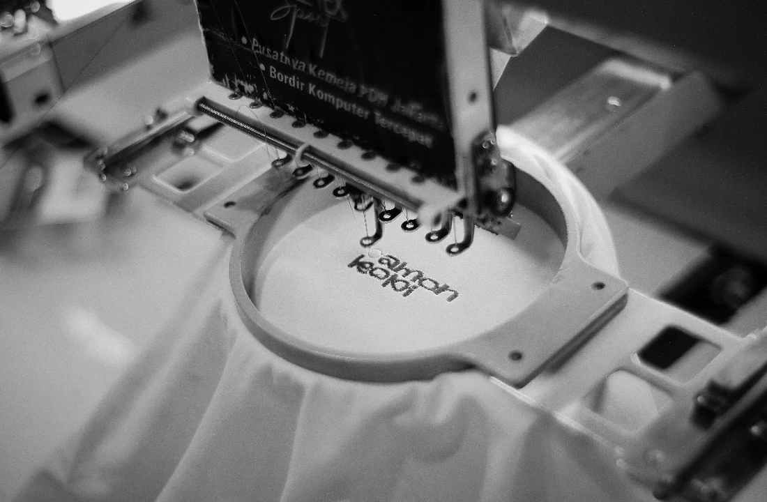 Custom embroidery image showing an embroidery machine stitching a logo onto white fabric, suitable for premium branded apparel and stitched logo decoration