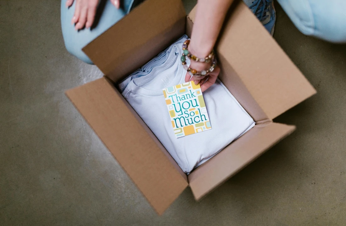 Custom apparel packaging image showing T shirts being packed with a thank you card, suitable for retail-ready finish, private label packaging, and scaling apparel production