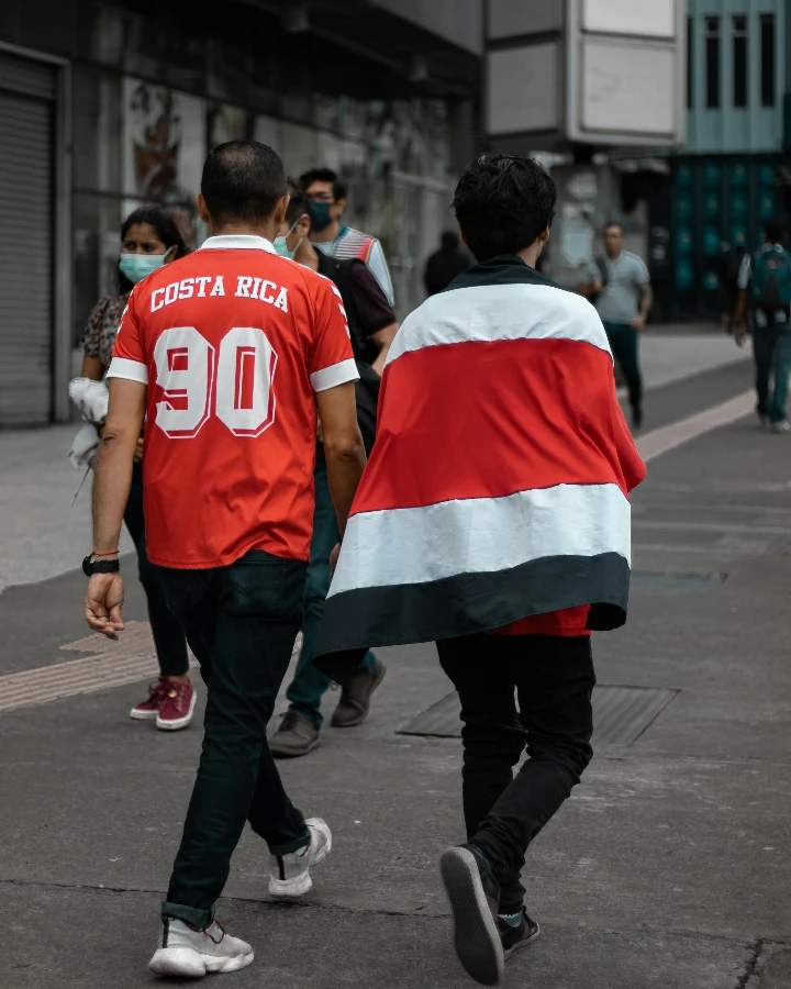 Soccer fans walking in team-inspired apparel on a city street, suitable for discussing soccer fan shirts, licensing risk, and fan merchandise boundaries