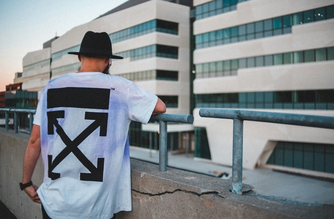 Man wearing an oversized white Print on Demand Streetwear T-shirt with a bold black arrow graphic on the back in an urban setting