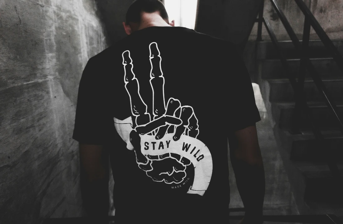 Man wearing a black Print on Demand Streetwear T-shirt with a large monochrome skeletal hand graphic printed on the back