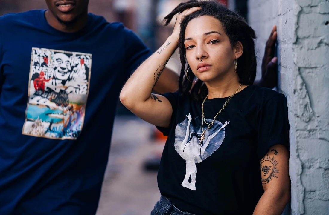 Two models wearing black and navy Print on Demand Streetwear graphic T-shirts in an urban fashion campaign
