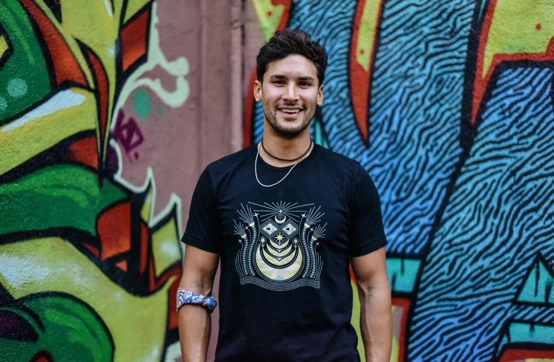 Man wearing a black geometric graphic T-shirt in front of a colorful graffiti wall, suitable for urban Print on Demand Streetwear branding