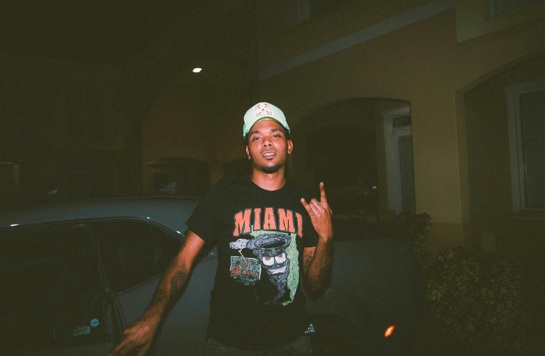 Man wearing a black Miami graphic T-shirt at night, suitable for Print on Demand Streetwear campaigns and city-inspired apparel collections