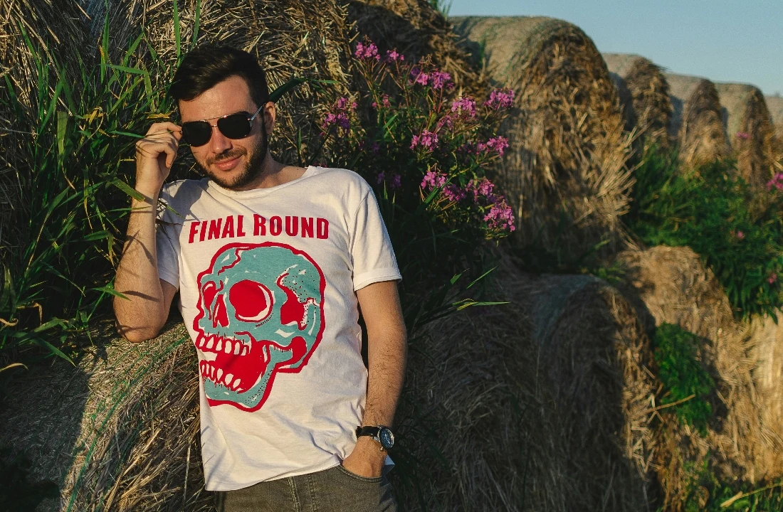 Man wearing a white skull graphic T-shirt outdoors, suitable for alternative Print on Demand Streetwear designs and seasonal apparel campaigns