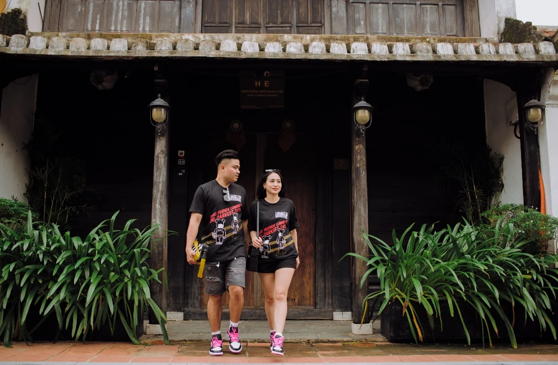 Man and woman wearing coordinated black graphic T-shirts outside a traditional building, showing a matching POD Streetwear collection