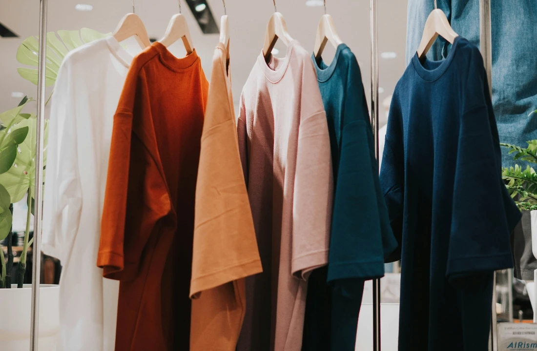 Oversized boxy tees in white, rust, beige, pink and navy displayed on wooden hangers