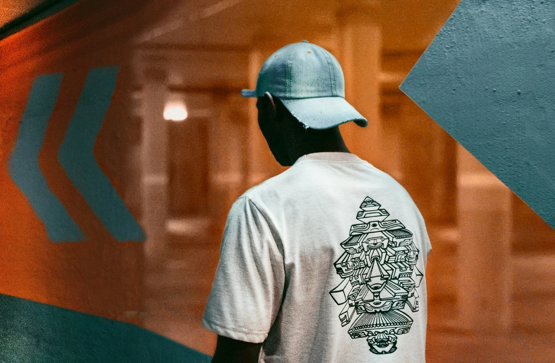Man wearing a white print on demand streetwear T-shirt with a detailed black back graphic in a modern hallway