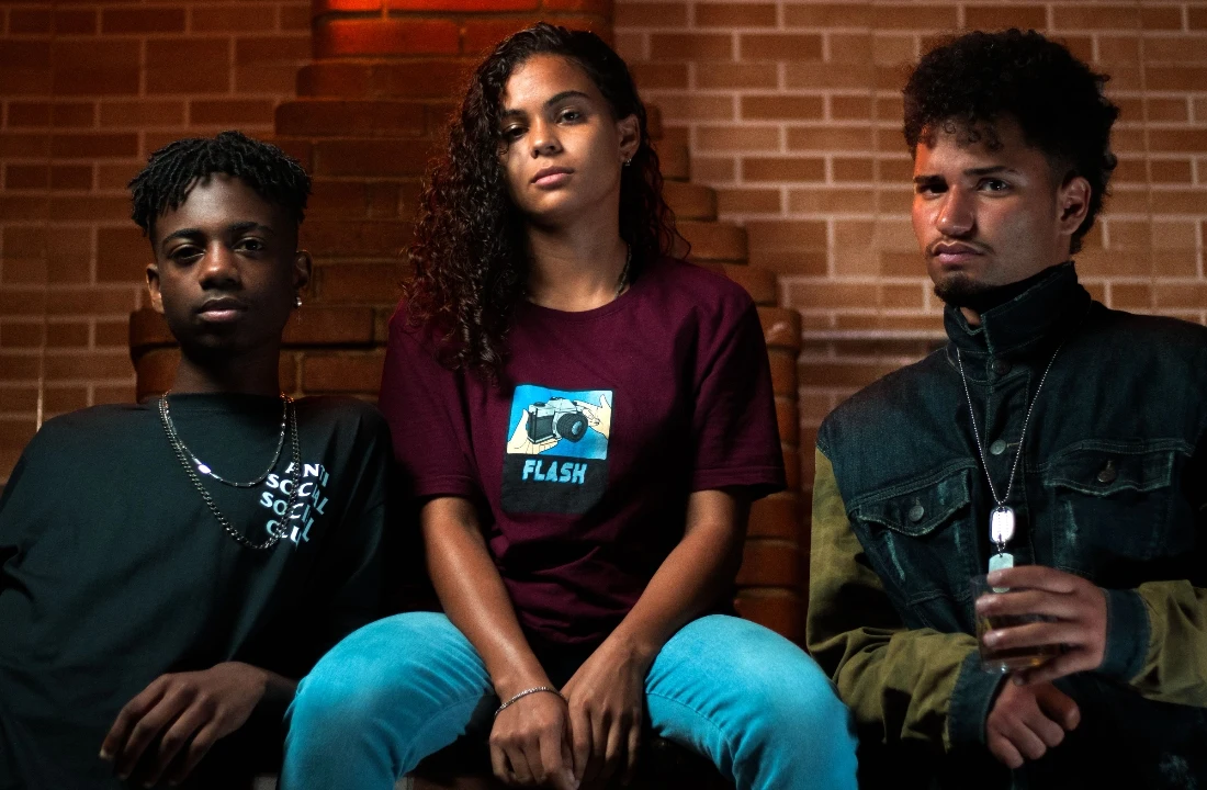 Three young adults posing indoors in POD Streetwear, featuring casual graphic T-shirts and layered street-style looks