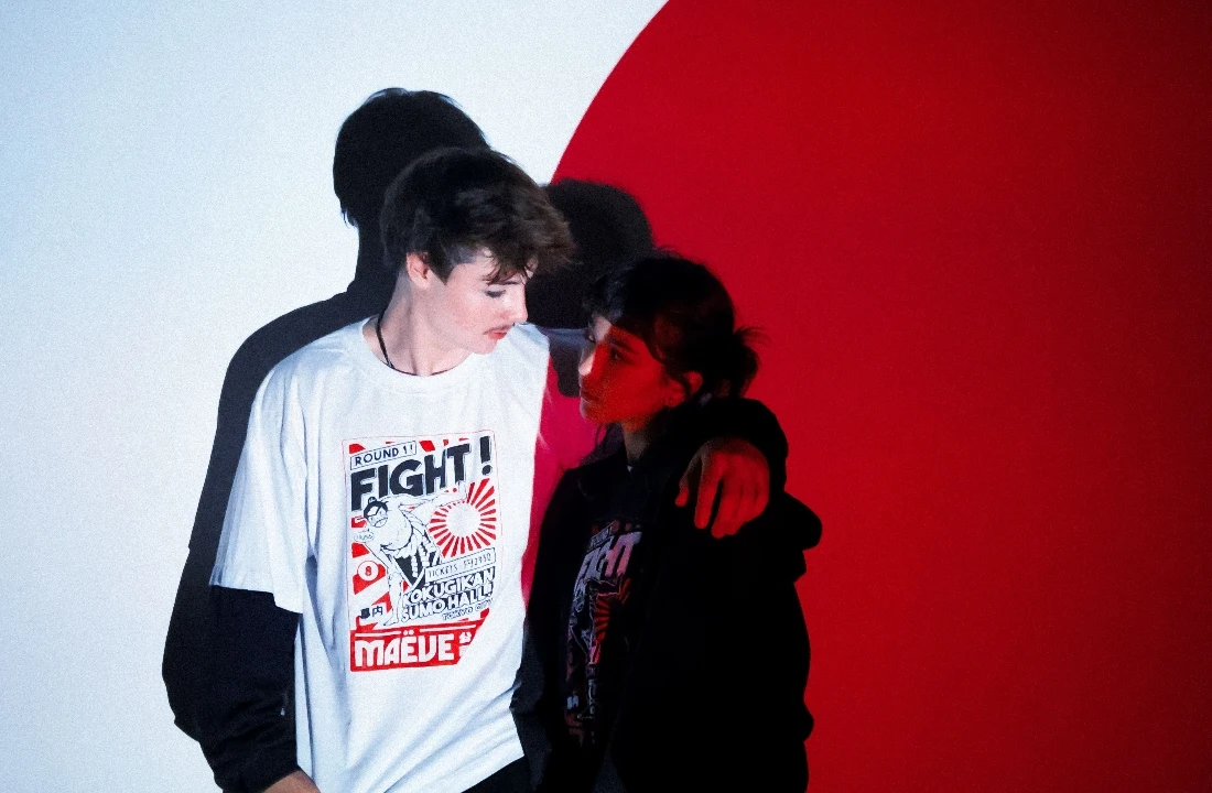 Two people posing under dramatic red-and-white lighting, wearing POD Streetwear including a graphic T-shirt and a dark hoodie