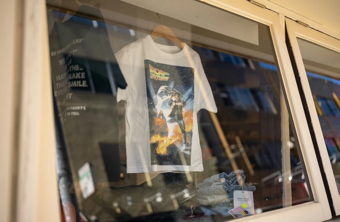Streetwear Print on Demand graphic T-shirt displayed in a shop window with folded apparel underneath