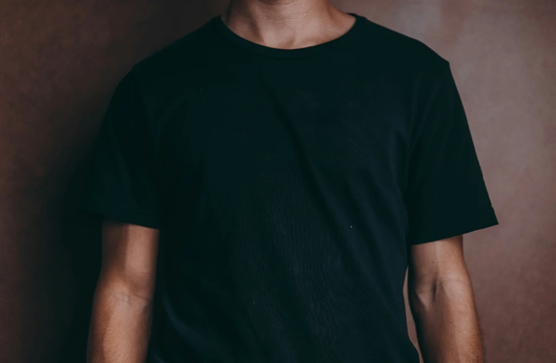 Close-up of a person wearing a plain black Heavyweight Cotton T Shirt for minimalist streetwear basics