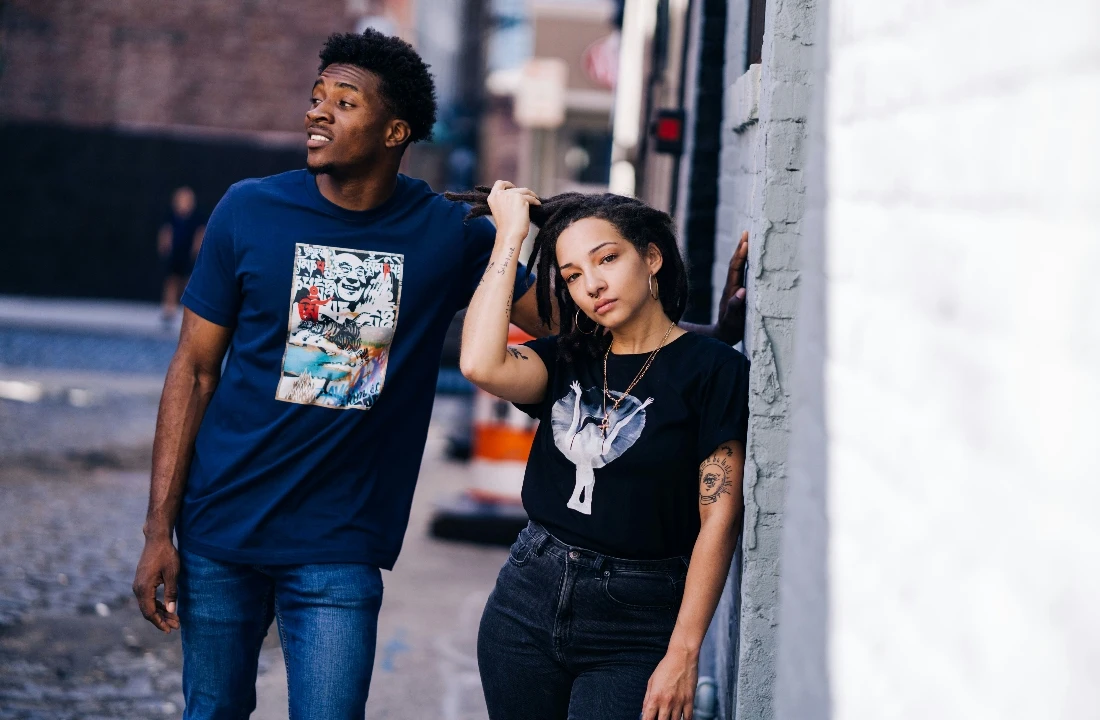 Two people posing in an urban setting wearing Print on Demand Streetwear graphic T-shirts in blue and black