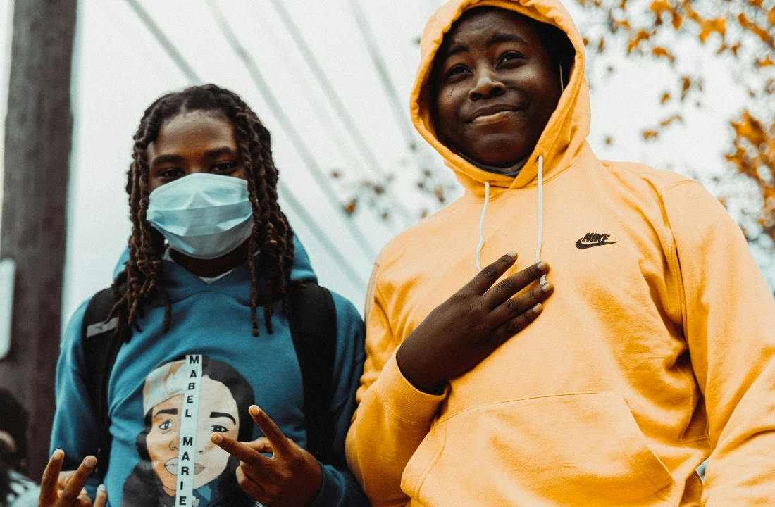 Two young people outdoors wearing casual hooded streetwear, including a blue Custom Streetwear Hoodies graphic design and a yellow hoodie