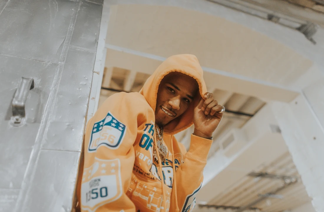Portrait of a man wearing an oversized peach Custom Streetwear Hoodies pullover with printed sleeve and chest details