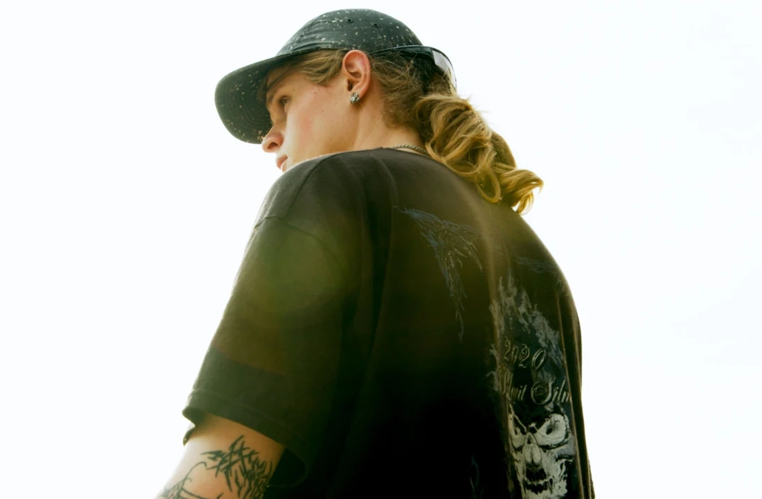 Side view of a model wearing washed t shirts with a faded black oversized fit and back graphic design