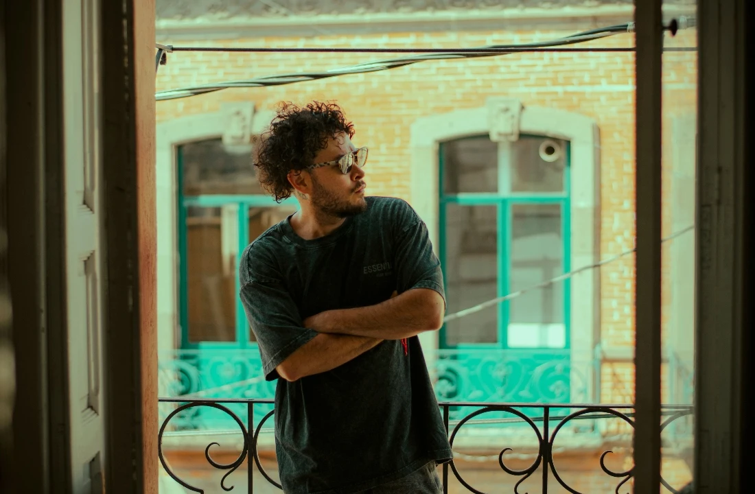 Man wearing washed t shirts in a relaxed dark color while standing on a balcony with vintage streetwear styling