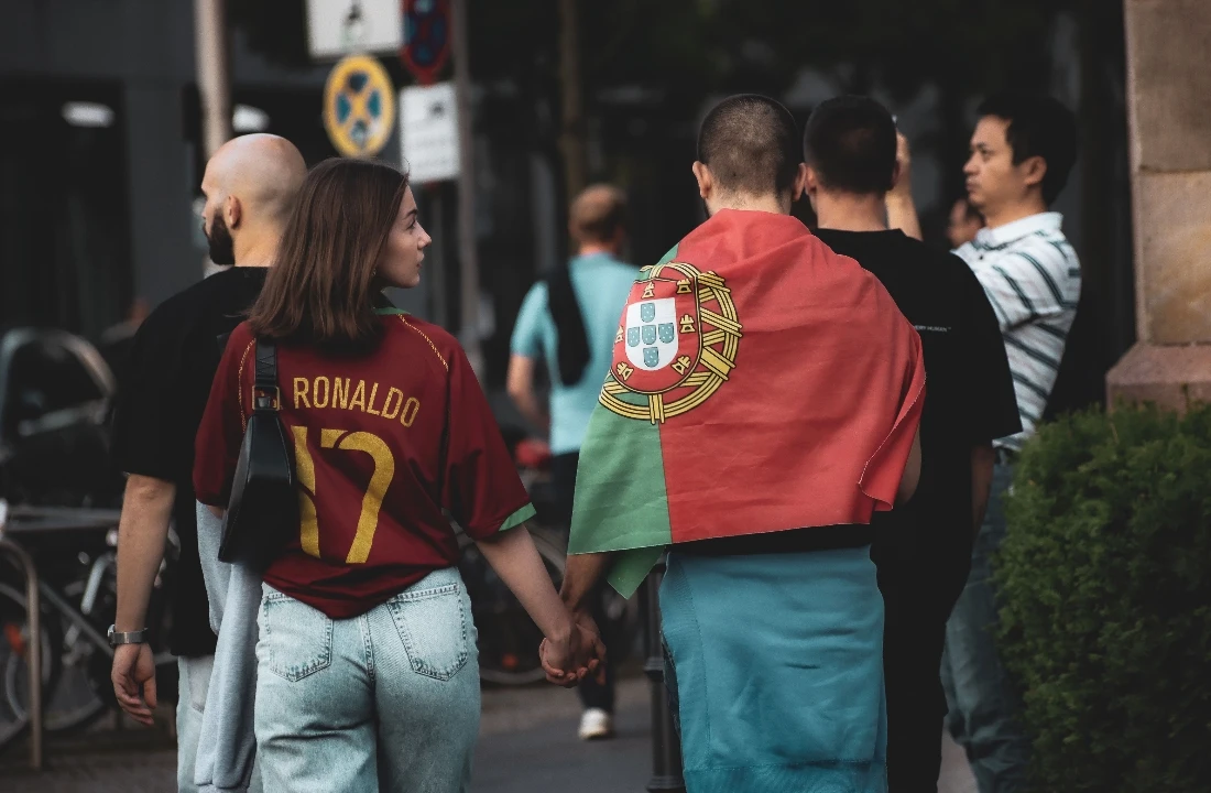 Couple walking in custom football shirts and a national flag during a football match day street event