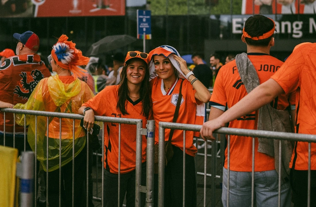 Football fans wearing orange custom football shirts and team colors outside a stadium event entrance