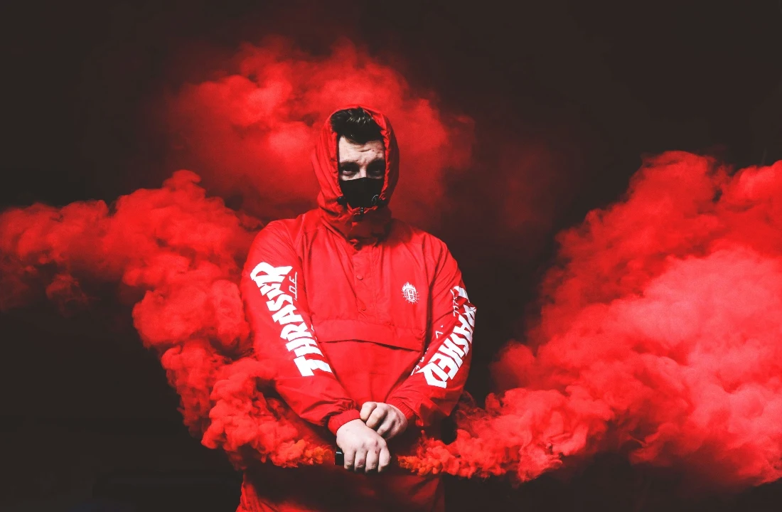 Person wearing a red hooded streetwear jacket surrounded by red smoke for dramatic Grunge Streetwear styling