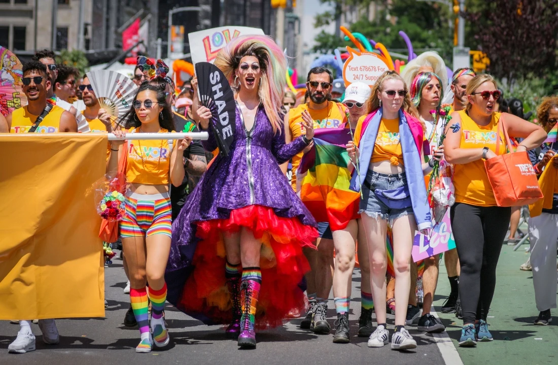 Group of people marching in colorful Pride Apparel with rainbow accessories during a street parade