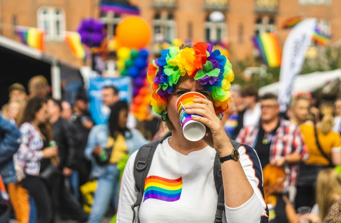 Person wearing a white sweatshirt with a rainbow flag design at a Pride event, showing colorful Pride Apparel styling