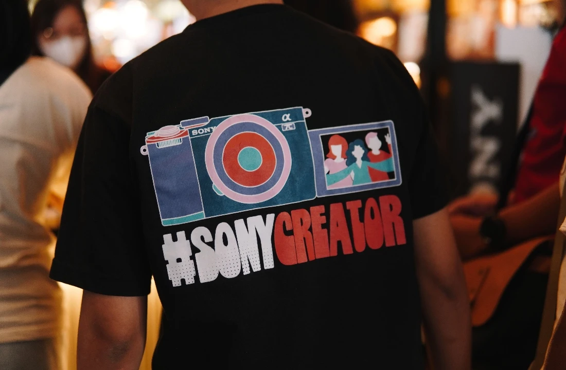 Back view of a person wearing a black print on demand streetwear T shirt with a large creator-themed graphic print
