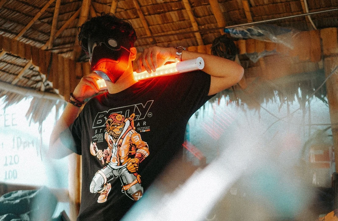 Person wearing a black print on demand streetwear graphic T shirt with a bold illustrated design and neon light props