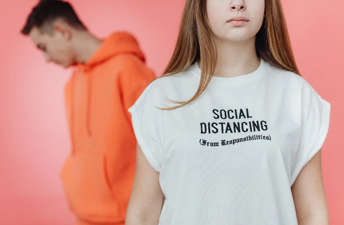 Model wearing a white POD T shirt with a small chest text print against a soft pink background