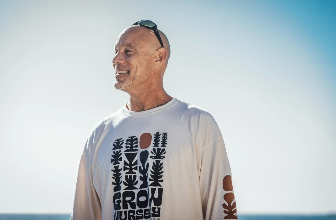 Man wearing a relaxed white POD T shirt with a front graphic print in bright outdoor light