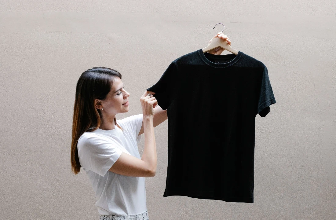 Woman holding a black best t shirt blanks sample on a hanger for custom apparel review