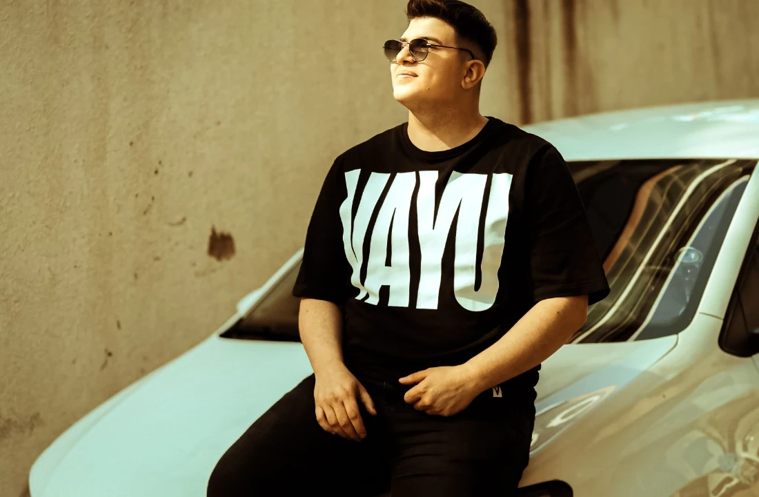 Man sitting on a car wearing a black Boxy Fit T Shirts style with bold front graphic for streetwear branding