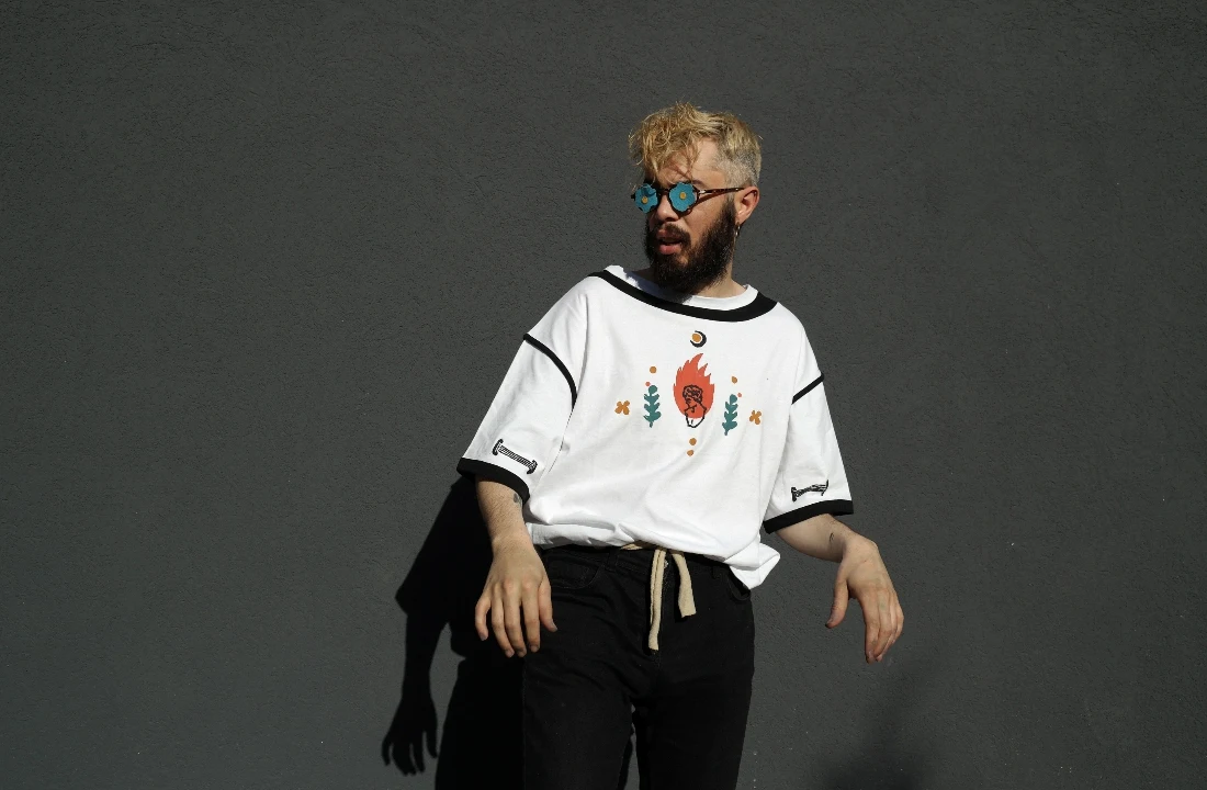 Man wearing a white Boxy Fit T Shirts style with graphic details and relaxed fit against a dark wall