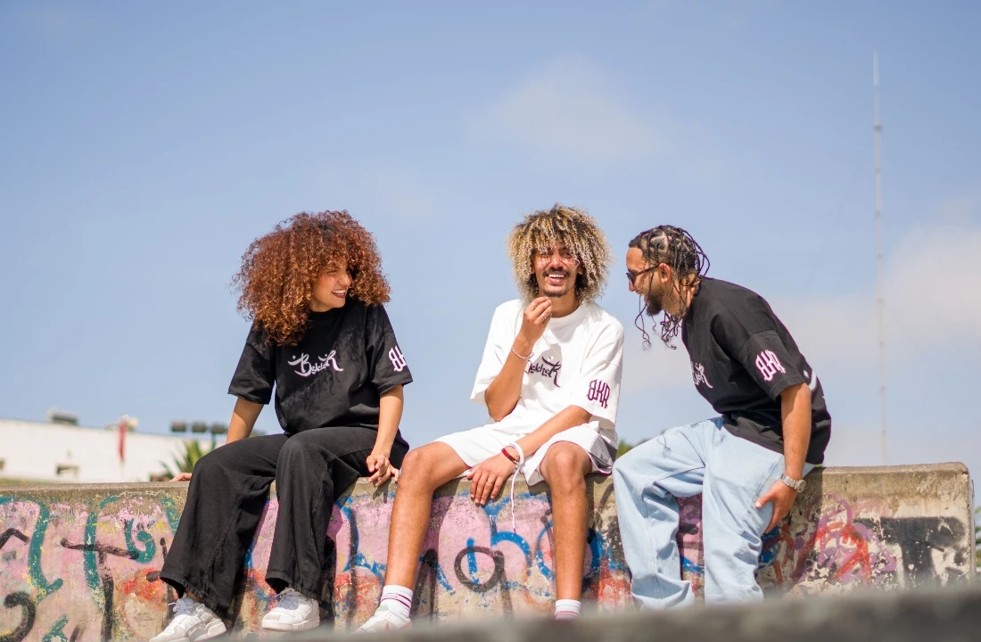 Three people wearing Heavyweight T Shirts in black and white styles with casual streetwear branding