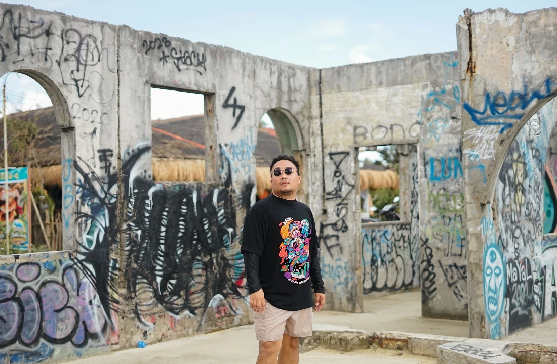 Man wearing a black streetwear graphic tee in a graffiti setting for a DTF vs DTG printing example