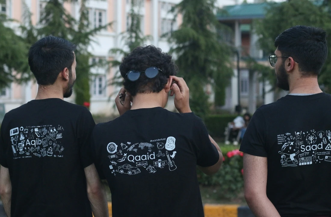 Three men wearing black T-shirts with detailed white back graphics for a screen printing vs DTF comparison