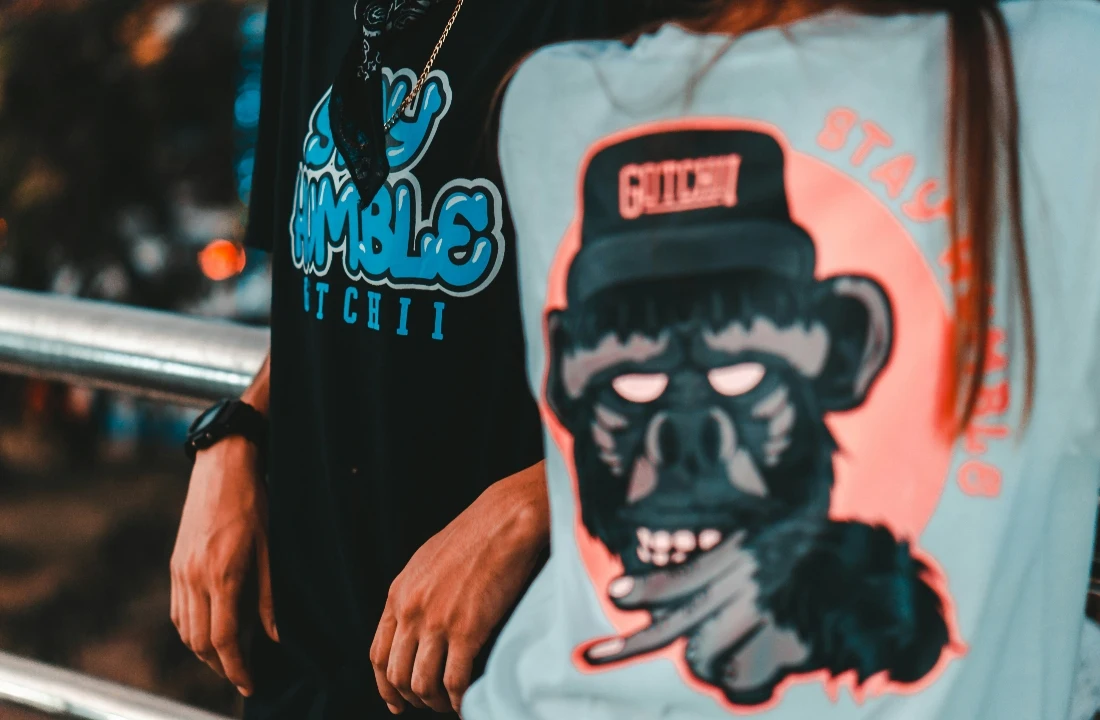 Two people wearing T-shirts with bold full-color artwork for comparing screen printing vs DTF print results