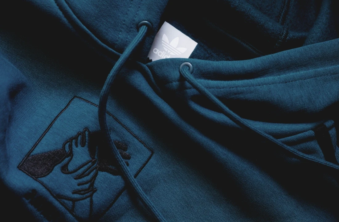 Close-up of a dark blue embroidery hoodie featuring custom stitched chest artwork and drawstring details