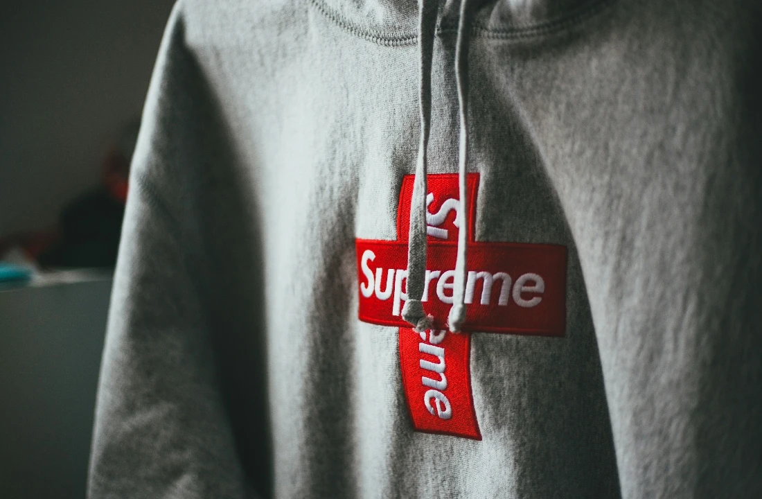 Grey embroidery hoodie featuring a red and white layered appliqué logo on the front chest