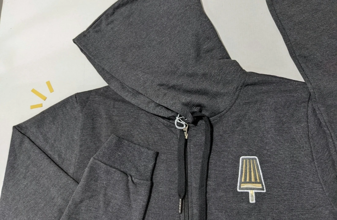 Grey zip-up embroidery hoodie featuring a small embroidered chest logo and front zipper