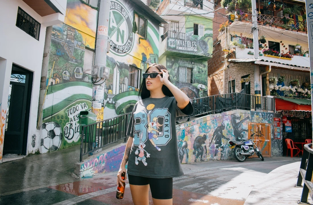 Woman wearing an oversized charcoal T-shirt with a colorful Jumbo Print cartoon design in an urban neighborhood