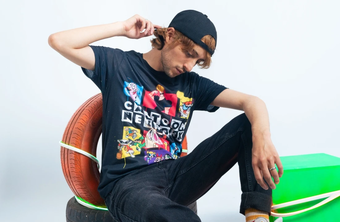 Man wearing a black streetwear T-shirt with a colorful Jumbo Print cartoon collage across the front