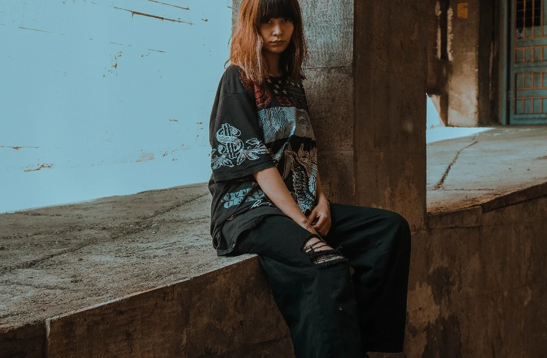 Woman wearing an oversized black T-shirt with a large multicolor Jumbo Print design across the front and sleeves