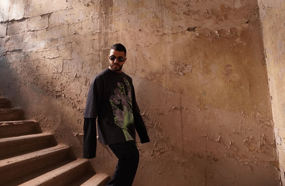 Man wearing a black layered streetwear T-shirt with a large green Jumbo Print hand graphic