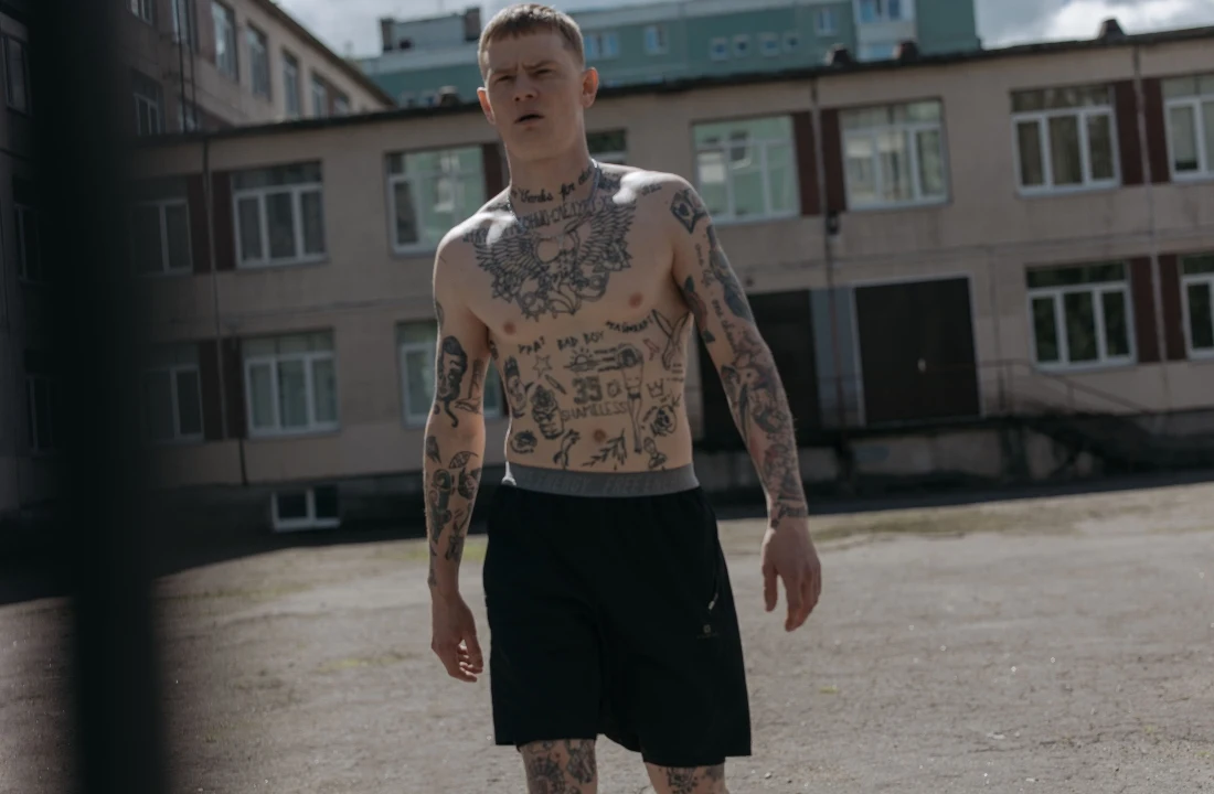Tattooed man wearing loose black athletic Streetwear Shorts in an urban courtyard