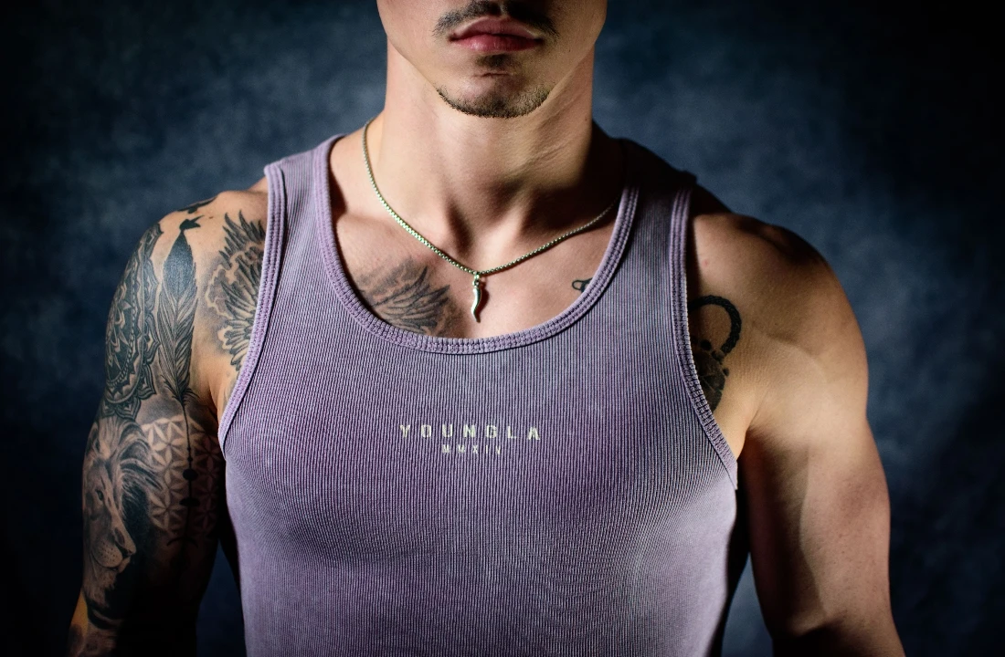 Close-up of a man wearing a purple ribbed Custom Tank Top with a small printed logo at the center chest