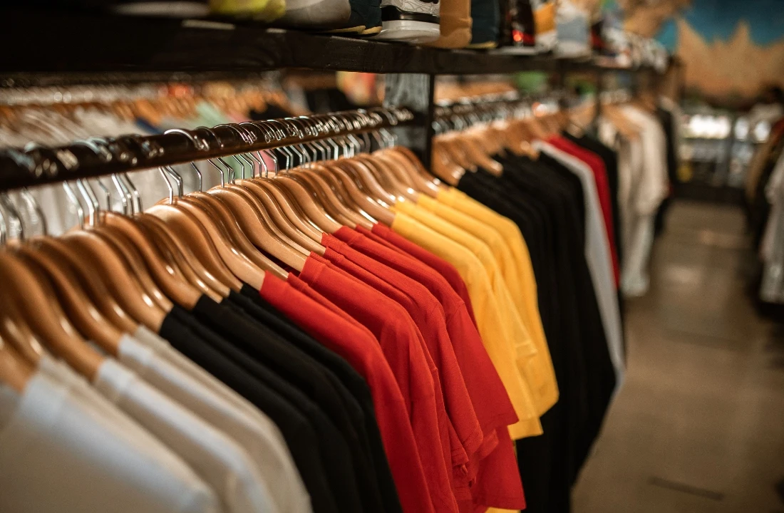 Colorful Custom Apparel T-shirts arranged on wooden hangers in a retail clothing shop