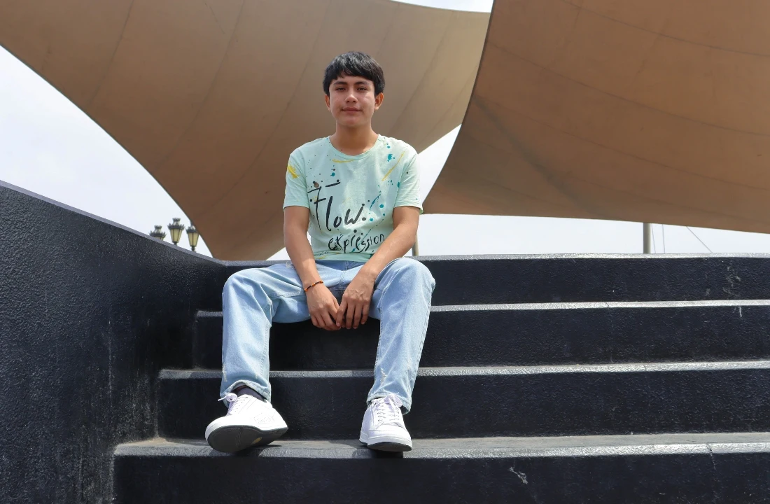 Young man wearing a light green printed T-shirt and jeans as a relaxed Festival Apparel outfit for outdoor events